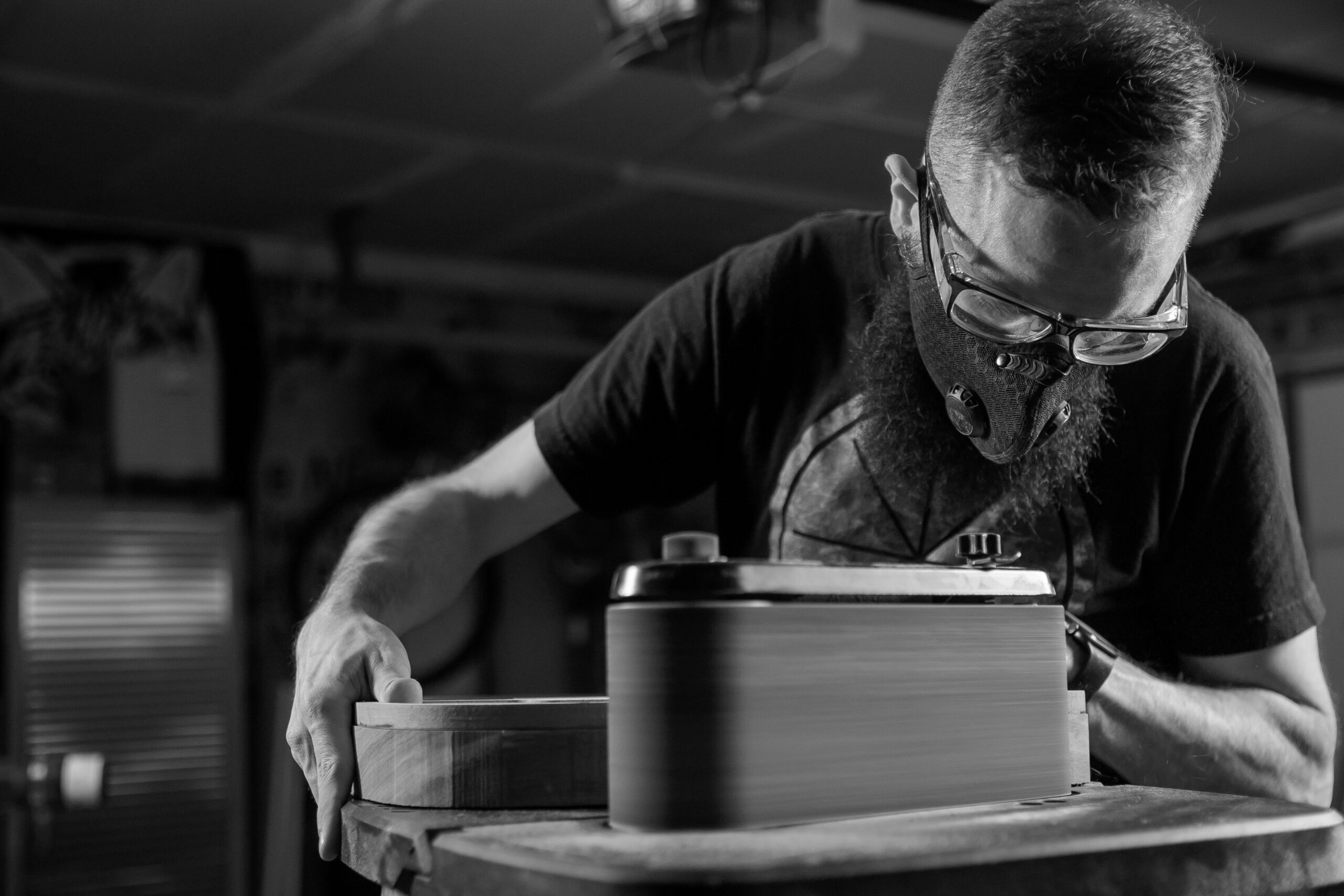 photo of Lucas Carter using a belt sander on a guitar body.